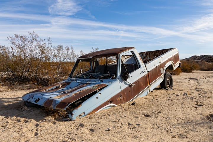 An old Ford pickup truck buried in the sand in Joshua Tree National Park, California